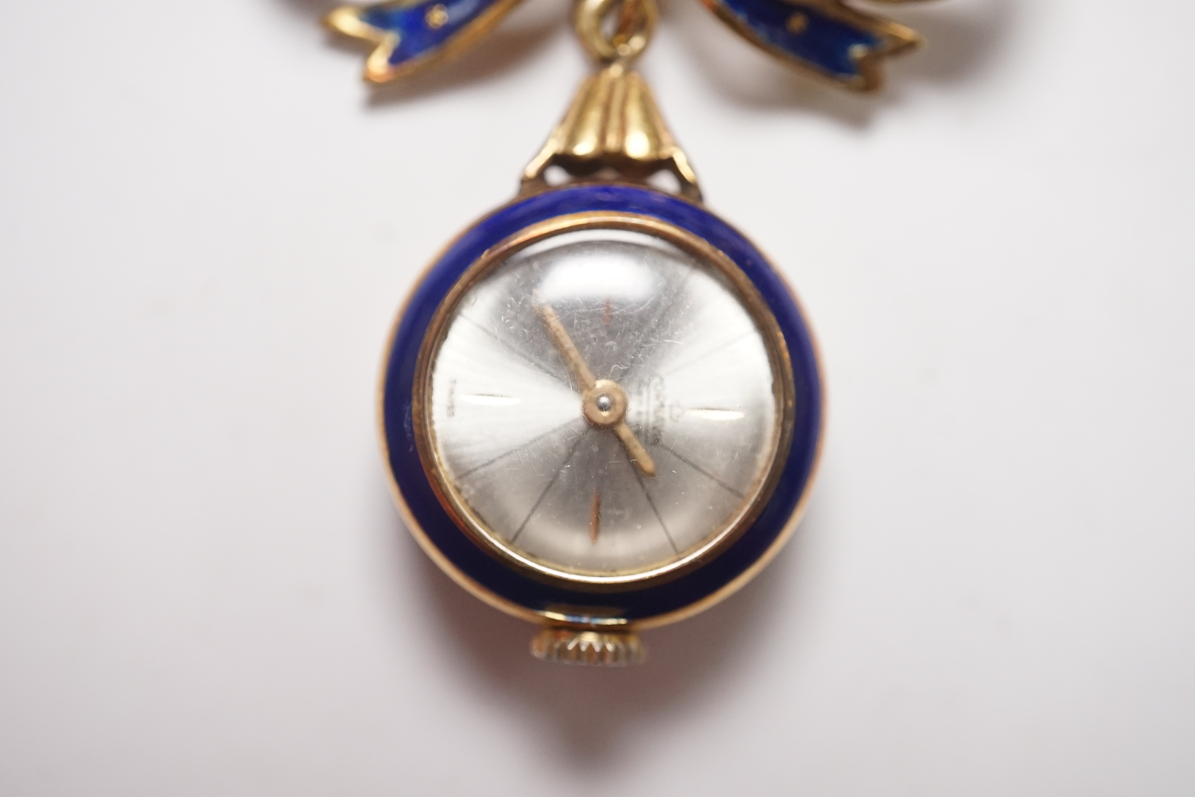 A mid 20th century Italian 750 and blue enamel fob watch, on a ribbon bow suspension brooch, overall drop 42mm, gross 10.9 grams. Condition - poor to fair